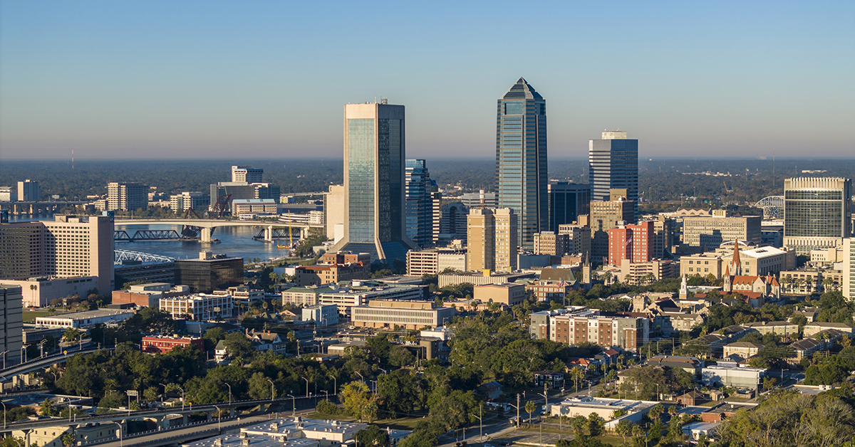 Drone aerial view overlooking downtown Jacksonville, Florida, with the Saint John's River, urban skyline, and waterfront on a clear day.