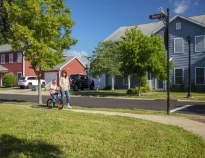 Knox-Hills military housing community. Woman walking with young boy who's riding a bicycle.