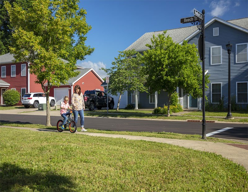 Knox-Hills military housing community. Woman walking with young boy who's riding a bicycle.