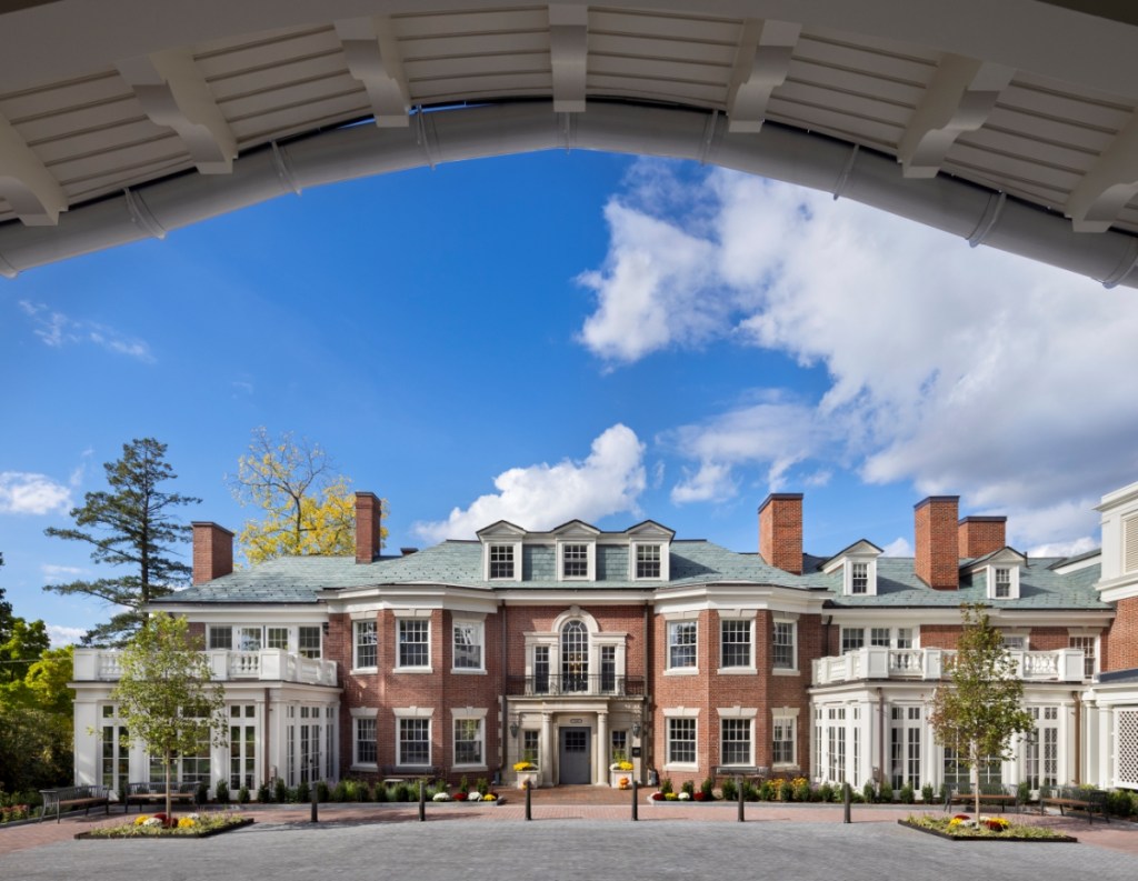 Historic Georgian Revival mansion, the Mitton House at The Newbury of Brookline, framed by a modern white arched portico.