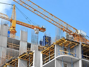 Crane and building construction site against blue sky. Image by Unkas Photo/Adobe Stock